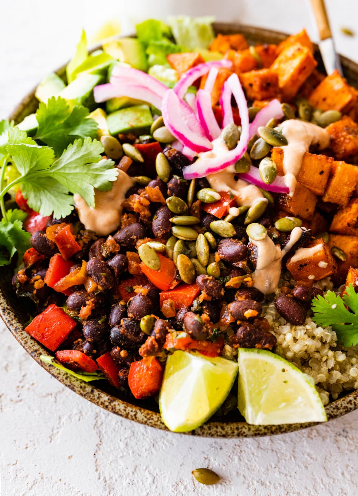 close up of roasted sweet potato black bean bowl with toppings. 
