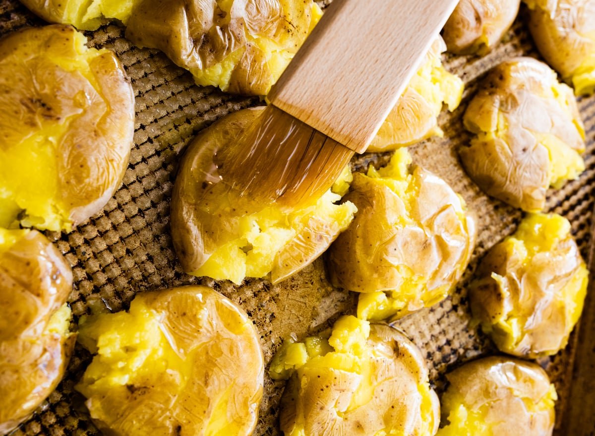 brushing smashed potatoes with butter with a brush. 