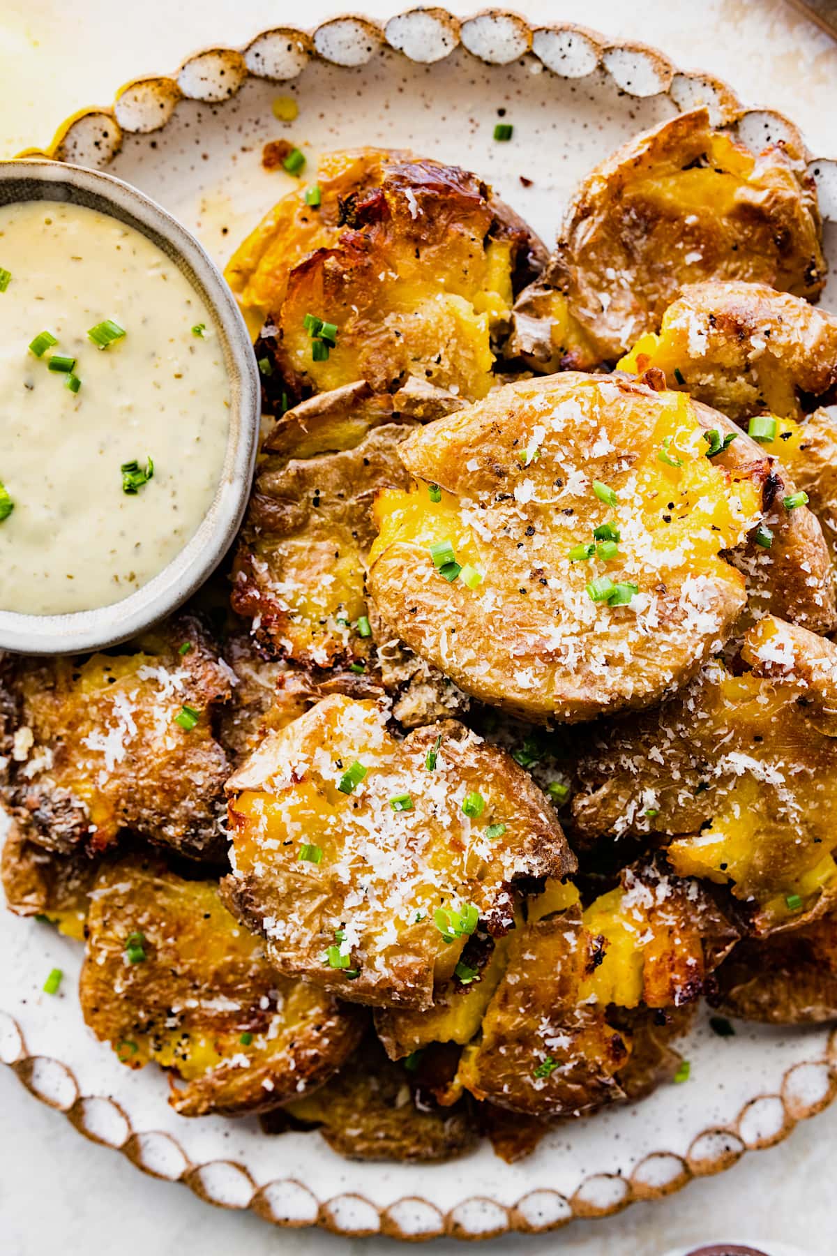 crispy smashed potatoes on plate with dipping sauce. 