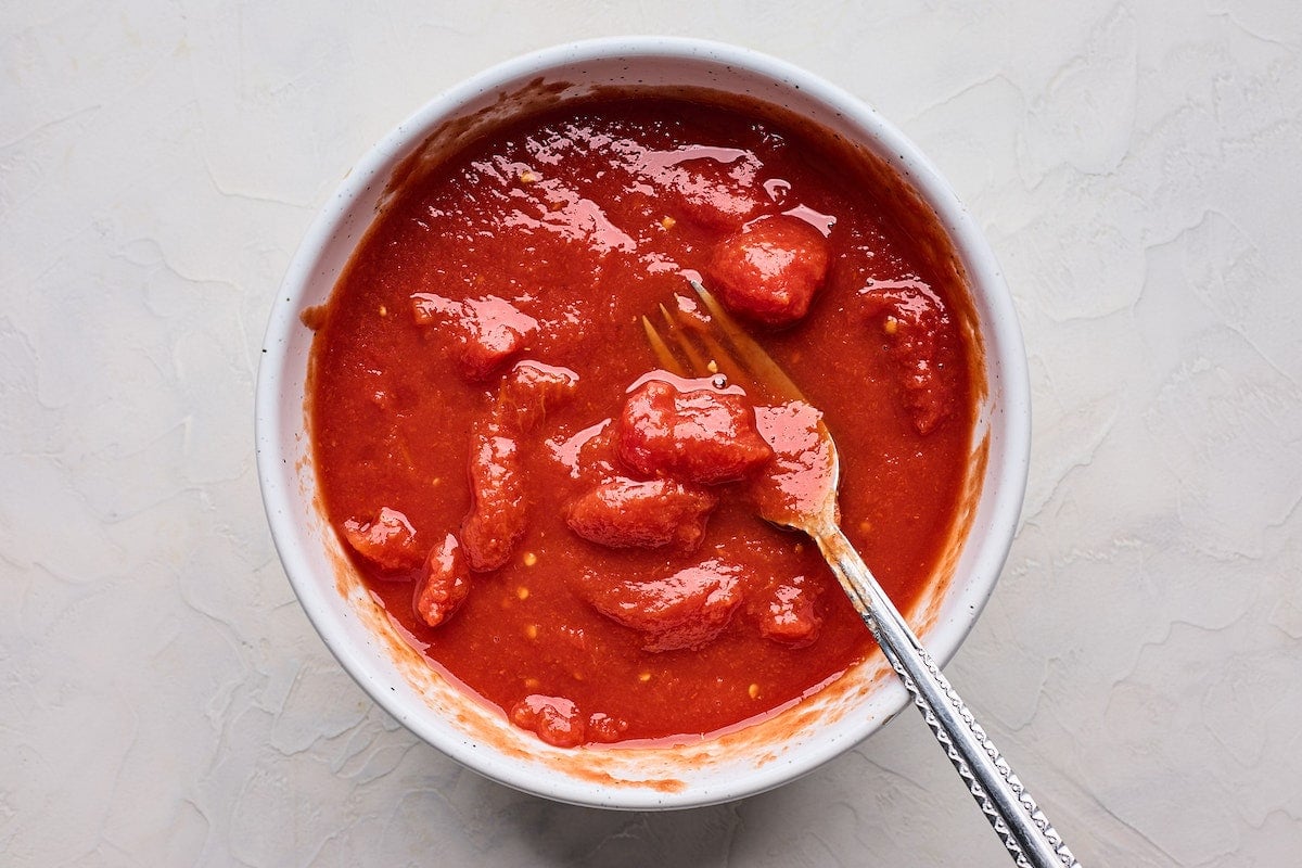 san marzano tomatoes in bowl with fork. 