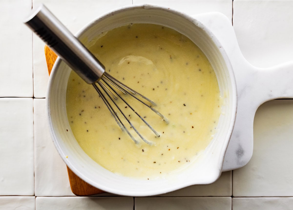 creamy lemon dressing in bowl with whisk. 