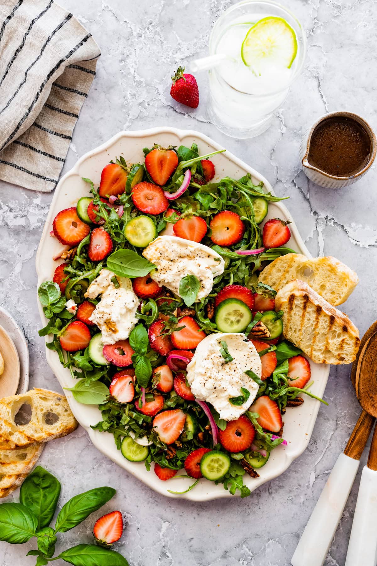 strawberry burrata salad on platter with balsamic vinaigrette and grilled bread. 