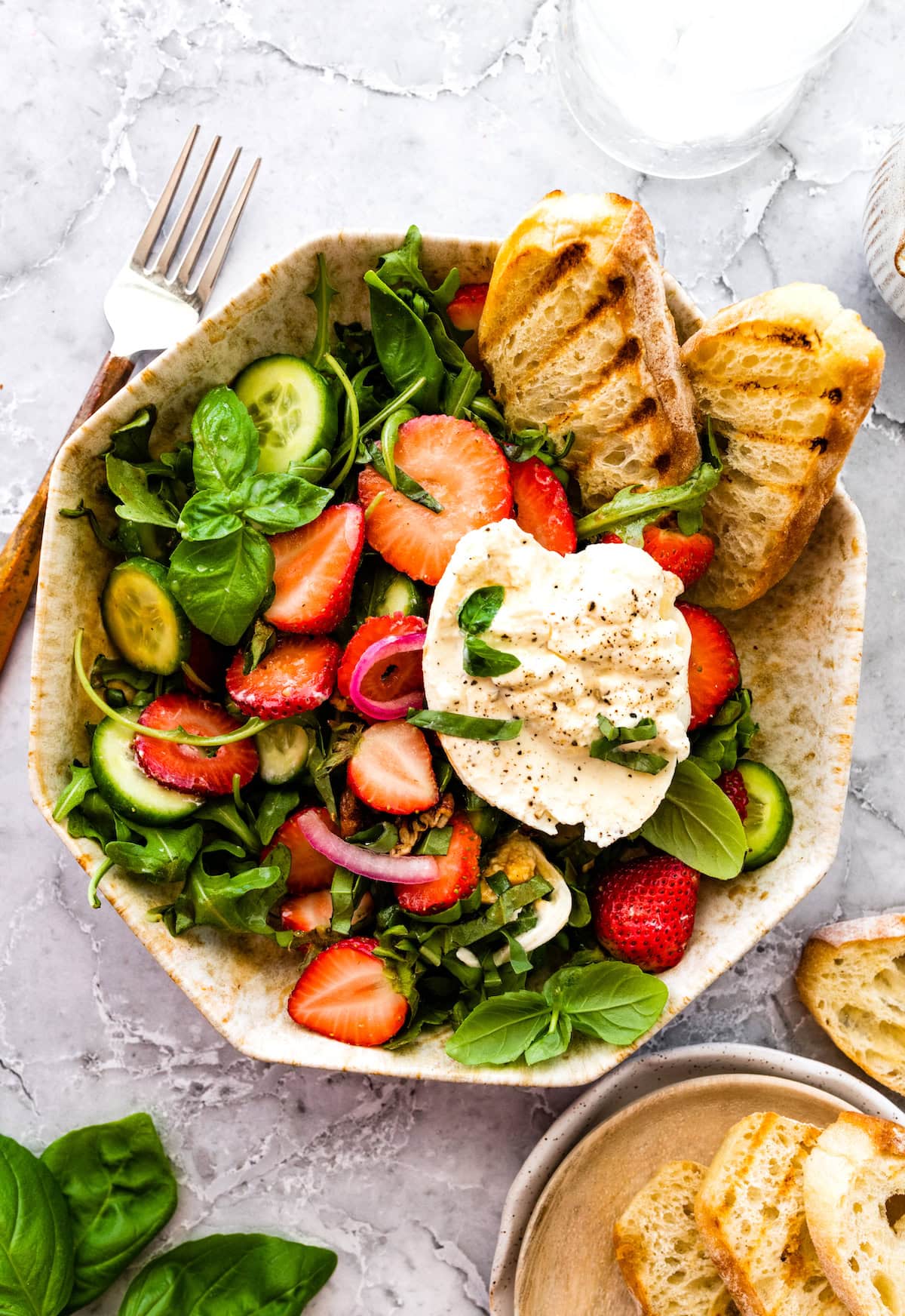 strawberry burrata salad in bowl with grilled bread. 