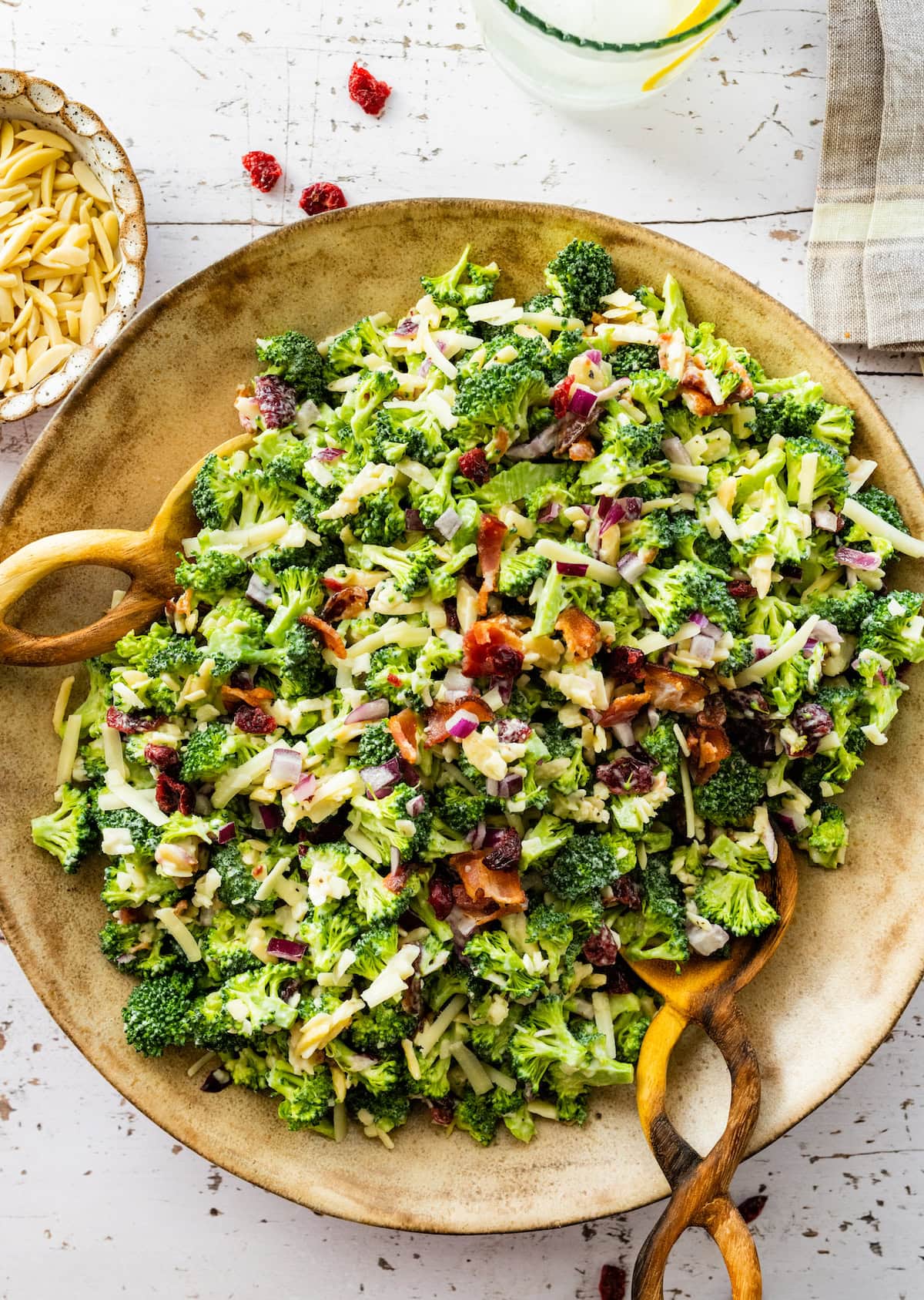 broccoli salad in serving bowl with salad servers. 
