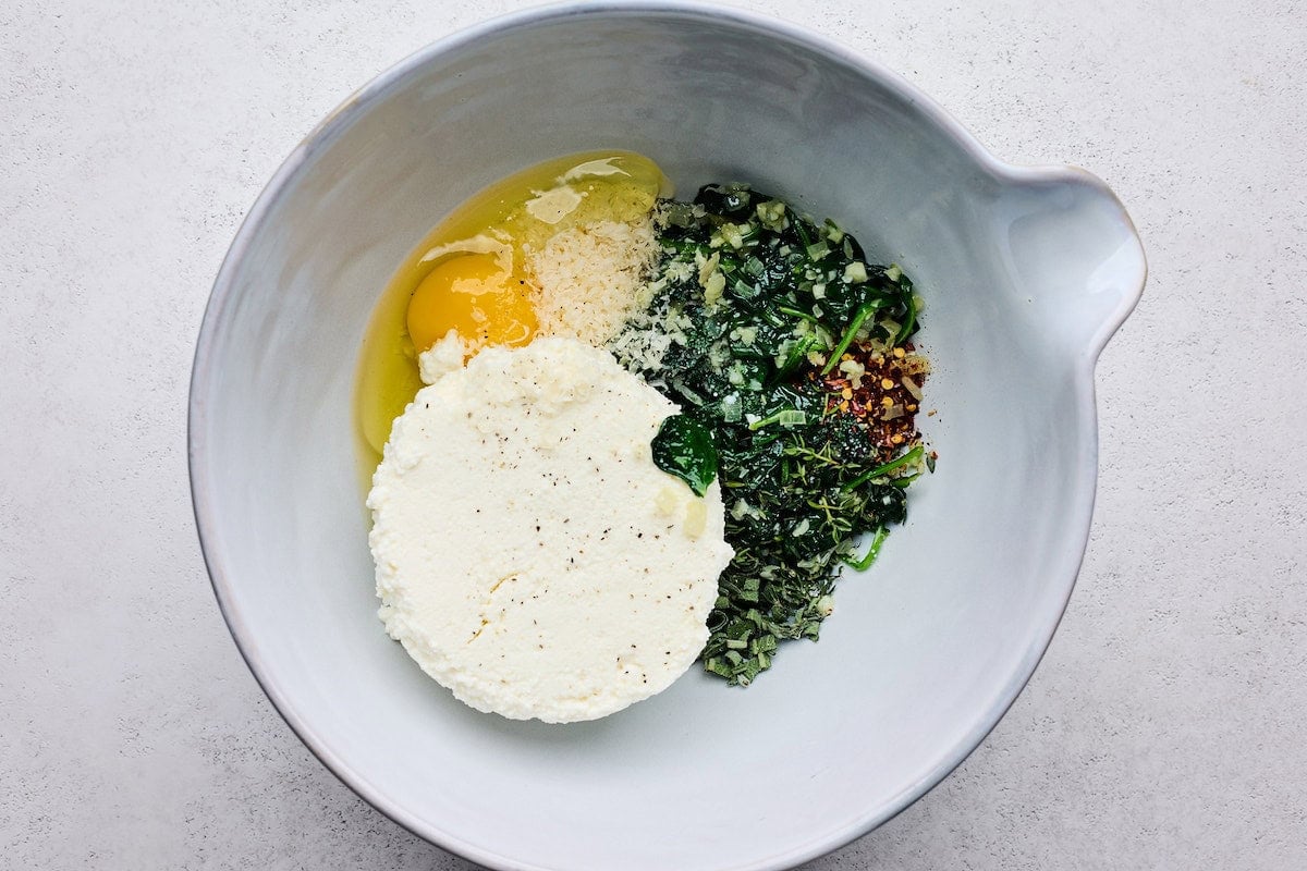 spinach, garlic, shallot, ricotta, egg, Parmesan cheese, and crushed red pepper flakes in bowl.