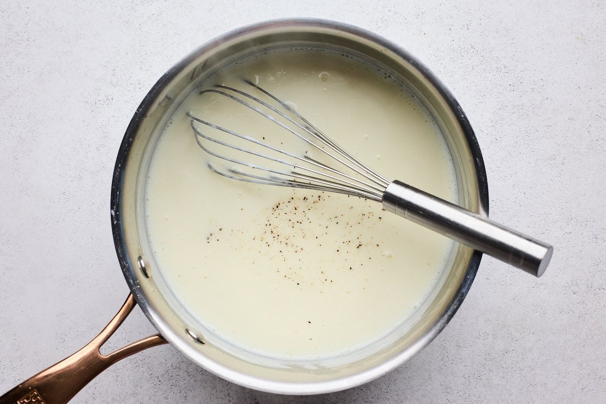 bechamel sauce in saucepan with whisk to make butternut squash lasagna.