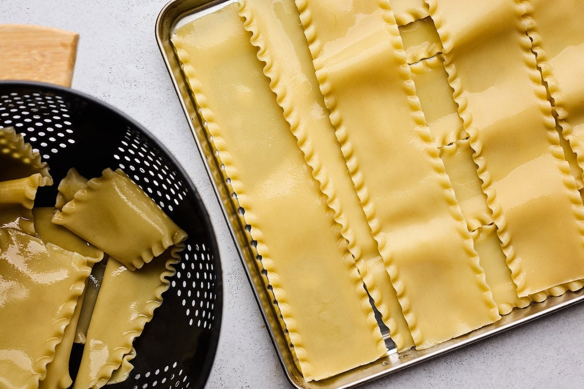 cooked lasagna noodles in colander and on sheet pan.