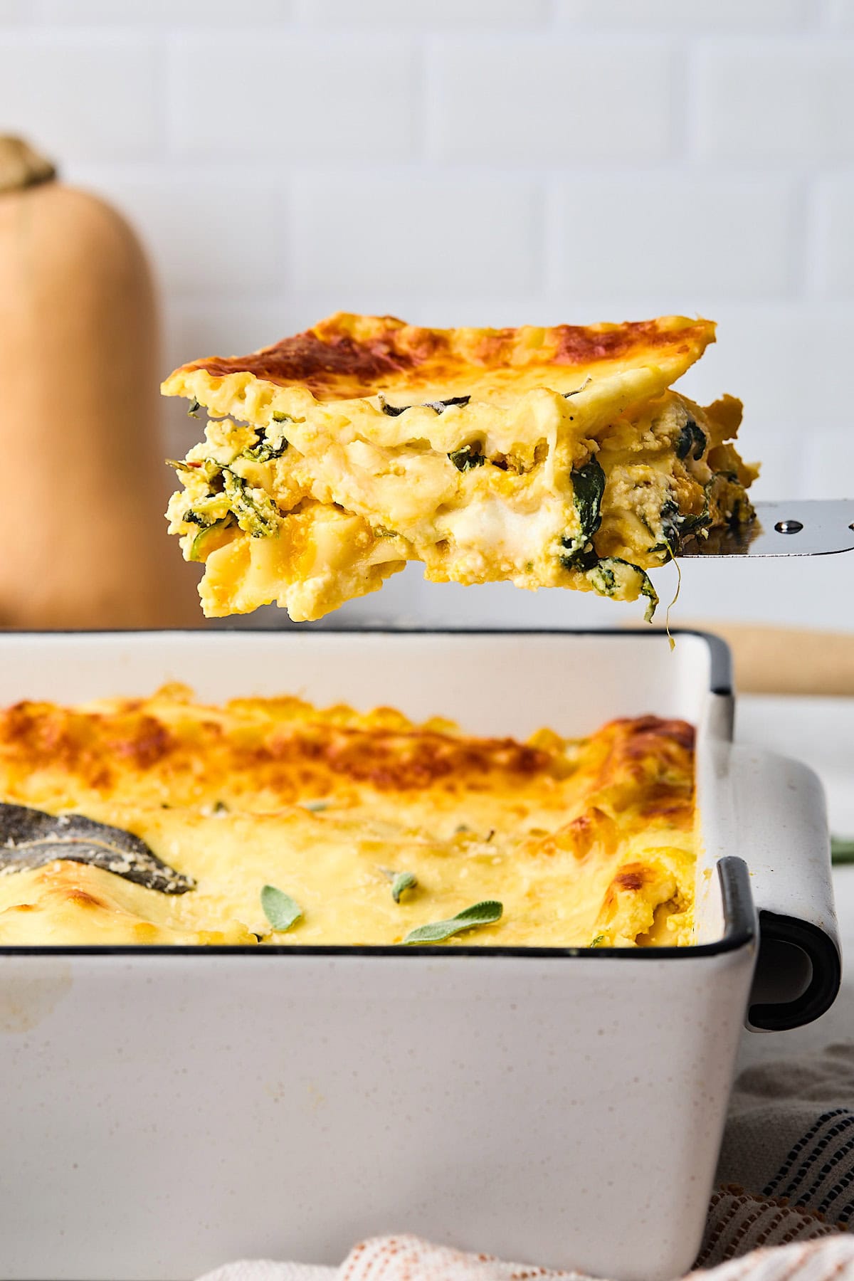 a piece of butternut squash being lifted out of the pan with a spatula.