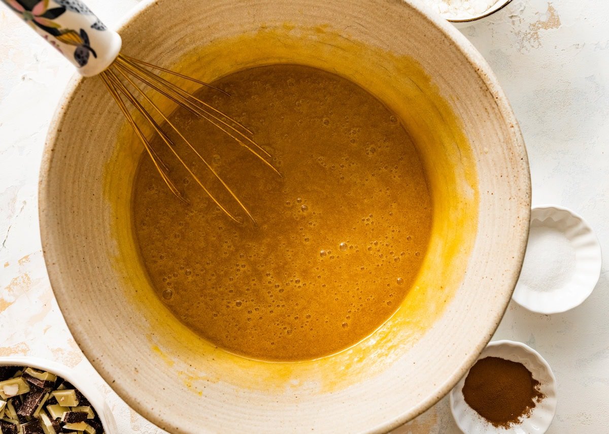 butter, sugars, eggs, and vanilla being whisked together in mixing bowl.