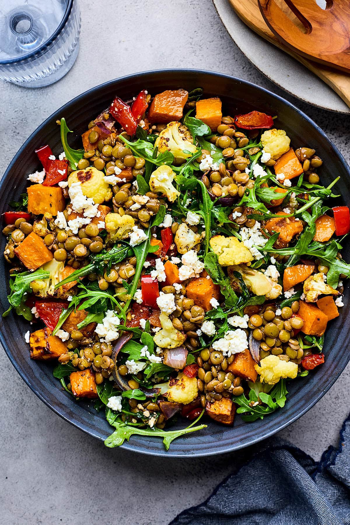 roasted vegetable lentil salad with arugula and feta cheese in bowl.