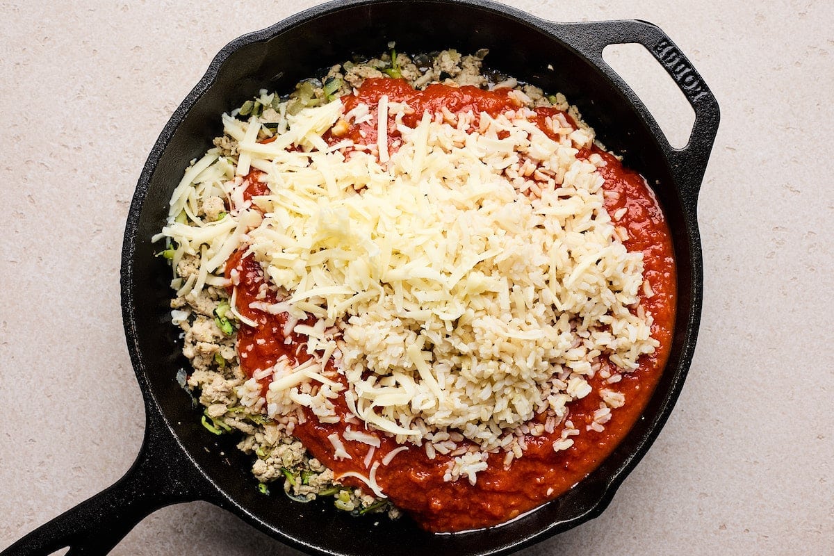 ground turkey, shredded zucchini, marinara sauce, rice, and shredded cheese in cast iron skillet.