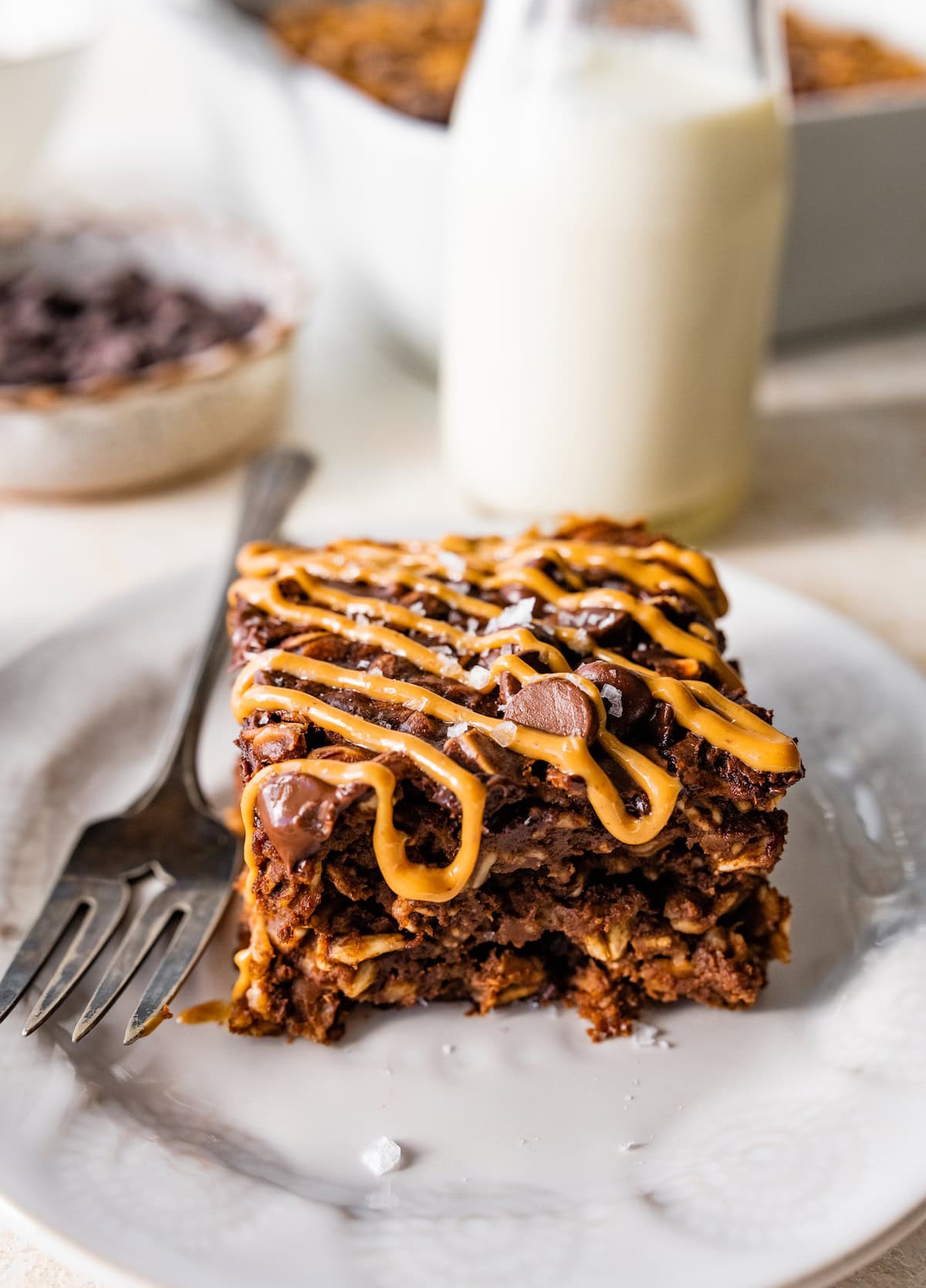 piece of chocolate peanut butter baked oatmeal with peanut butter drizzle and flaky sea salt on plate with fork.