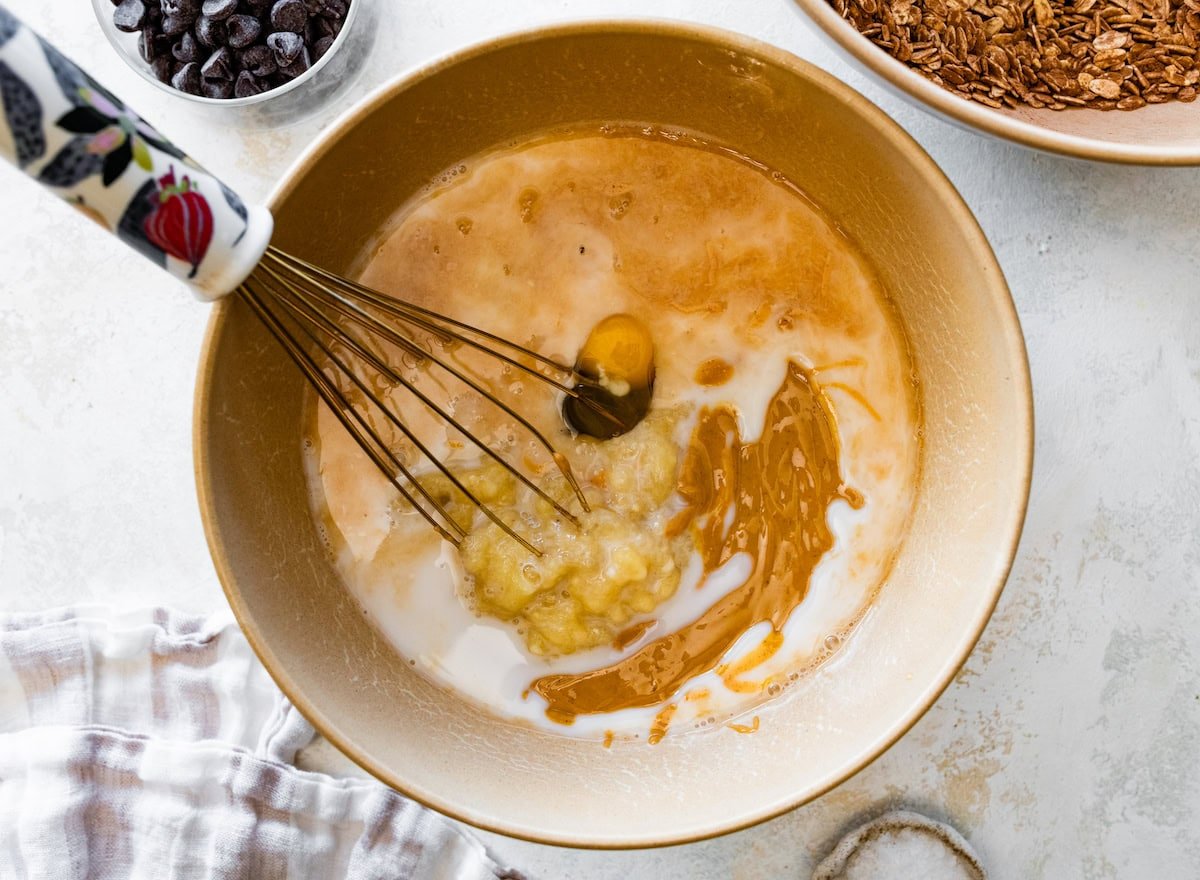 mashed bananas, milk, peanut butter, eggs, and vanilla in mixing bowl with whisk.