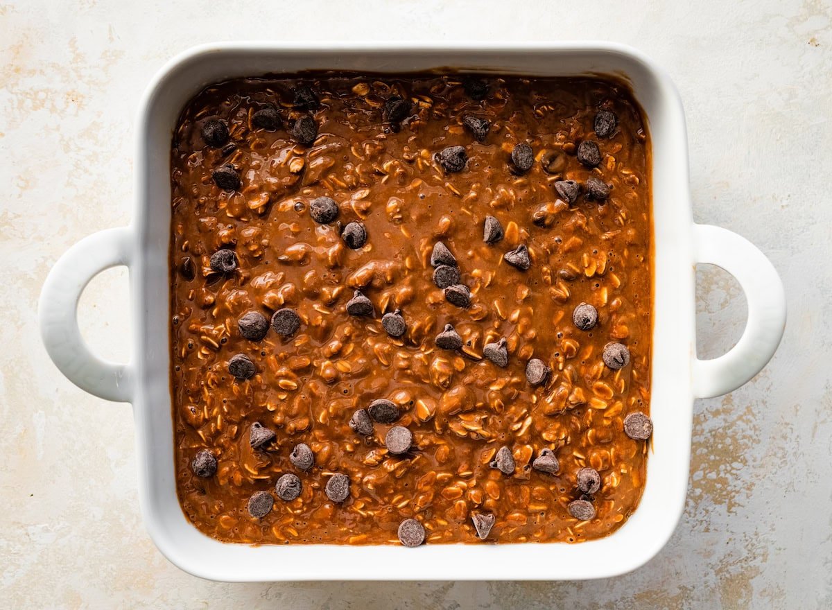 chocolate peanut butter baked oats batter in pan with chocolate chips sprinkled on top.