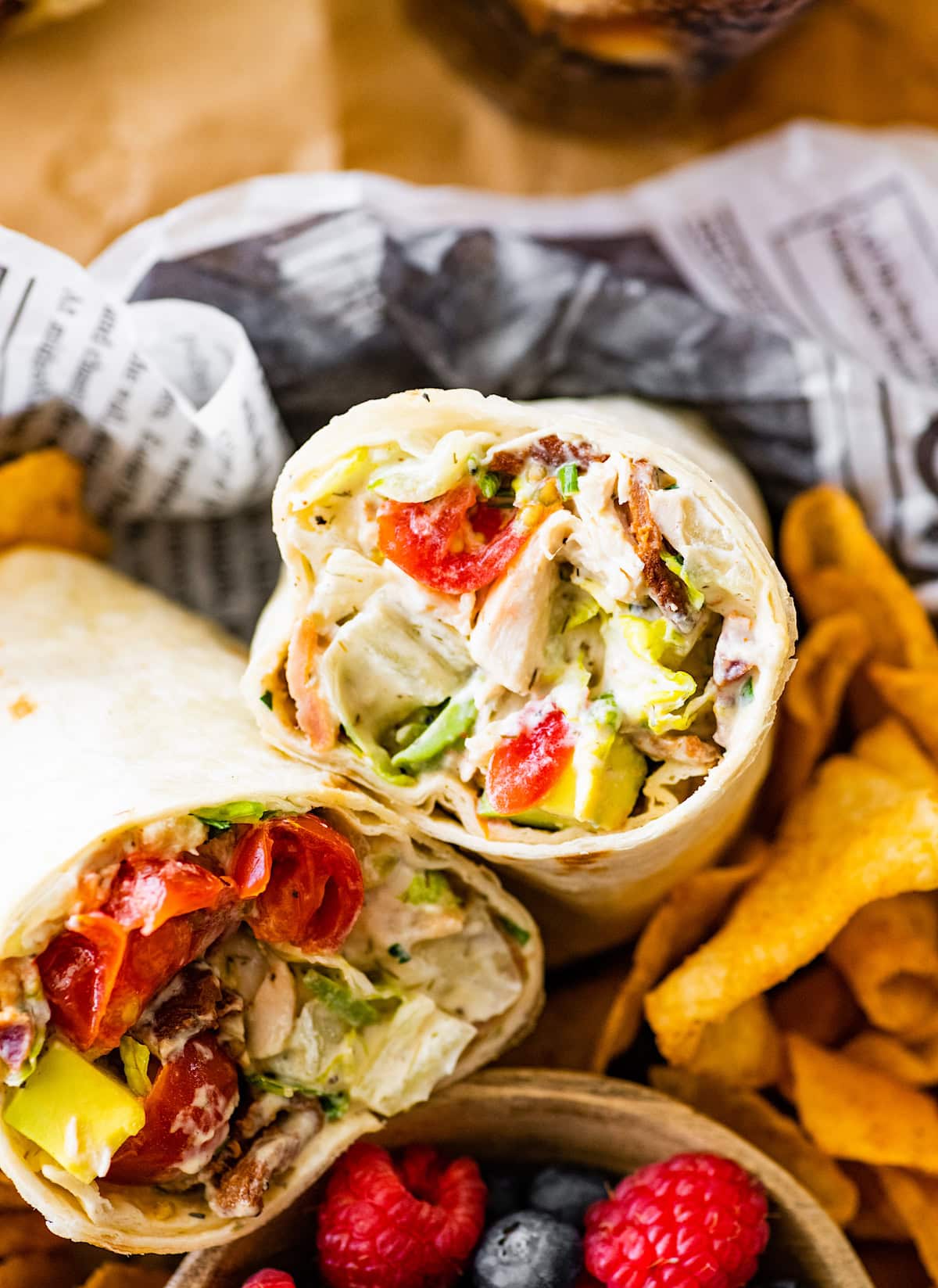 chicken blt wrap with chips and berries.