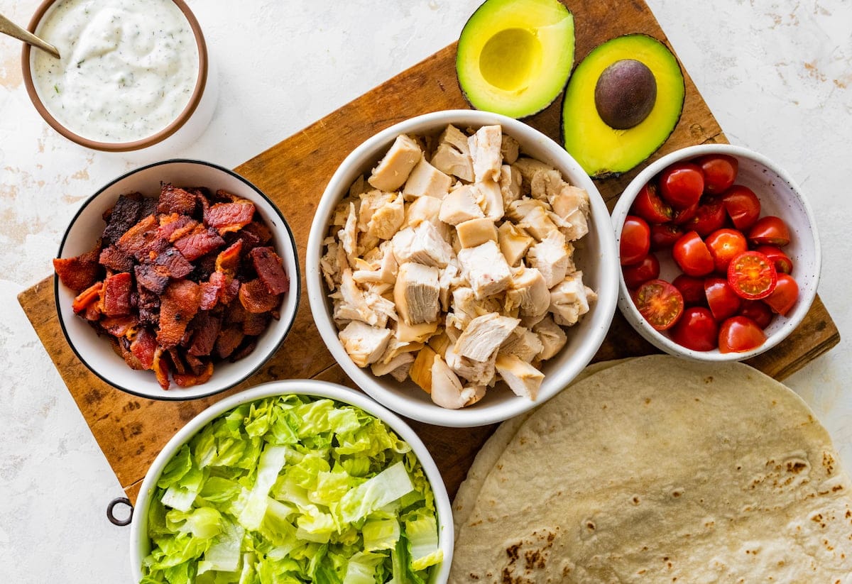ingredients in bowls to make chicken blt wraps.