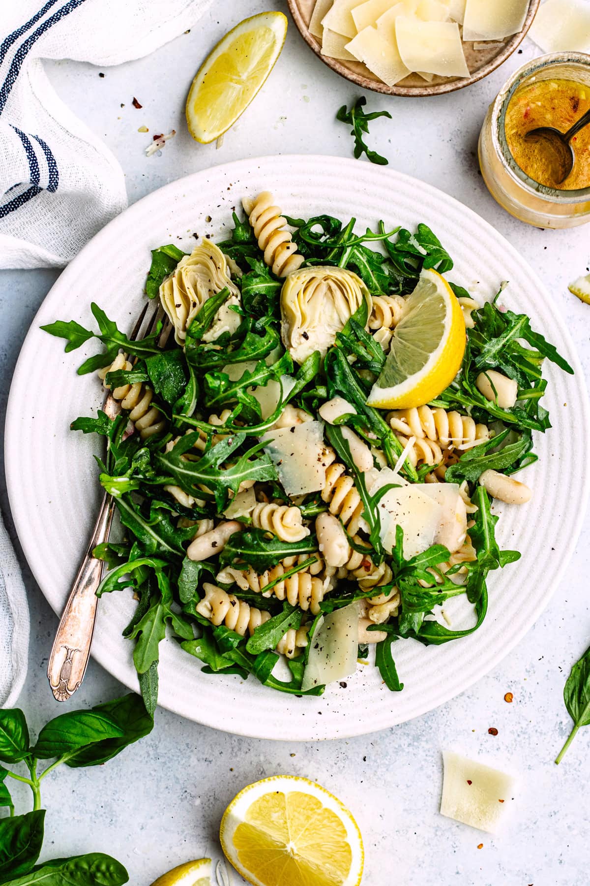 lemon artichoke arugula pasta salad on plate with fork. 