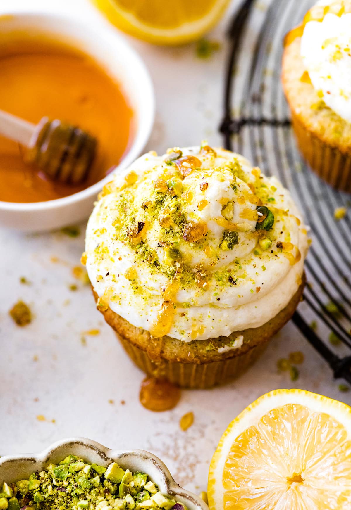 lemon pistachio cupcake with lemon buttercream, a drizzle of honey, and crushed pistachios.