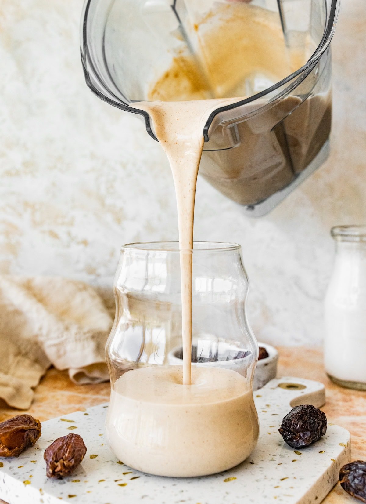 date shake being poured into a glass from a blender. 
