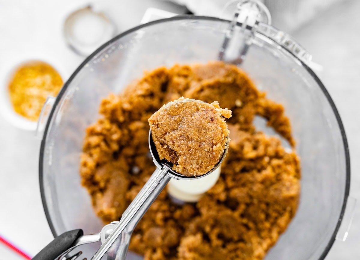 snickers protein ball filling being scooped out of a food processor.