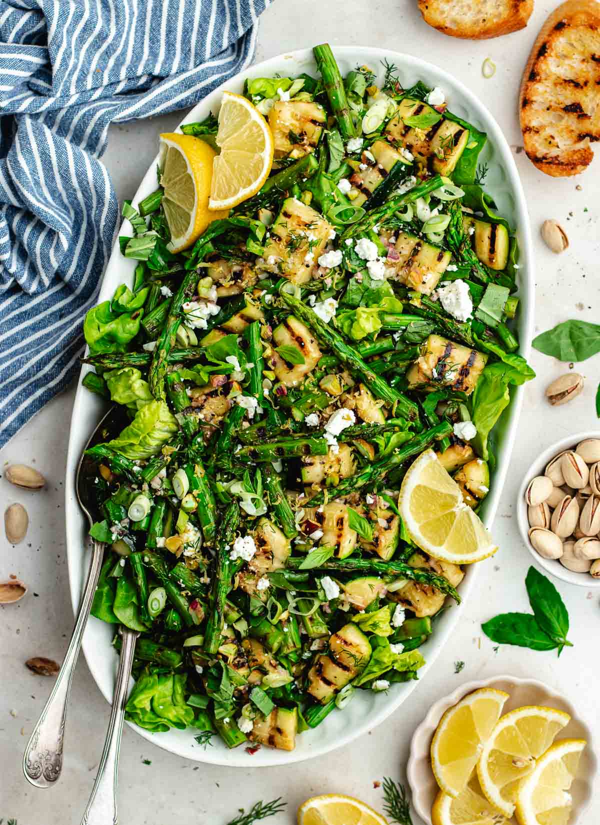 grilled asparagus and zucchini salad in serving bowl with serving spoon.