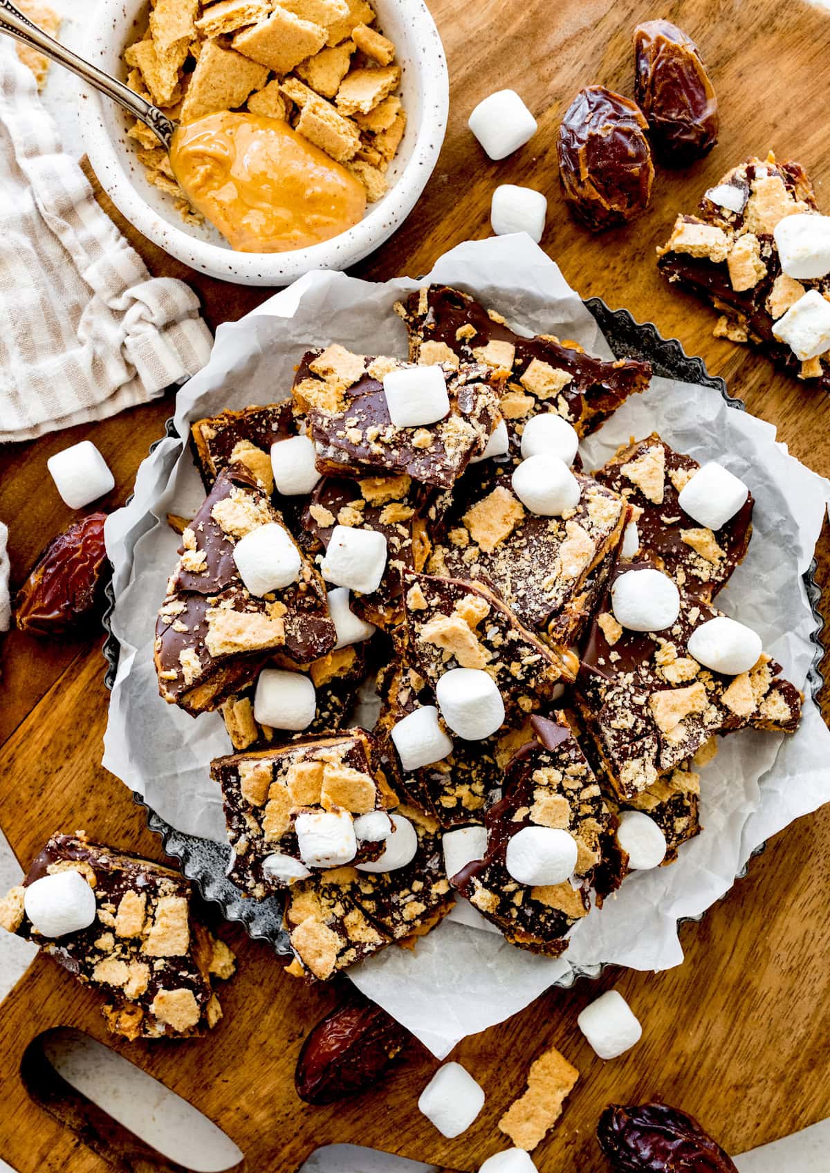 s'mores date bark with graham crackers and marshmallows in pan with parchment paper. 