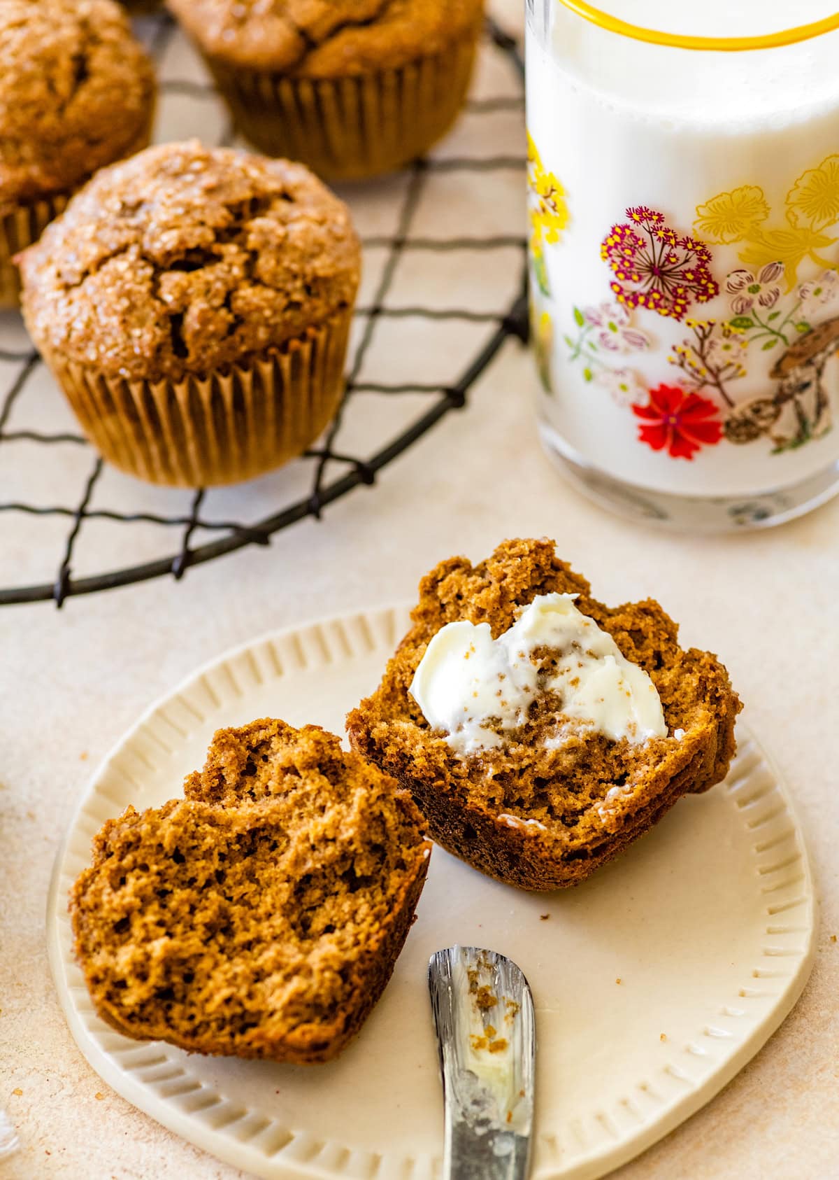 healthy pumpkin muffin cut in half with butter on plate with glass of milk. 