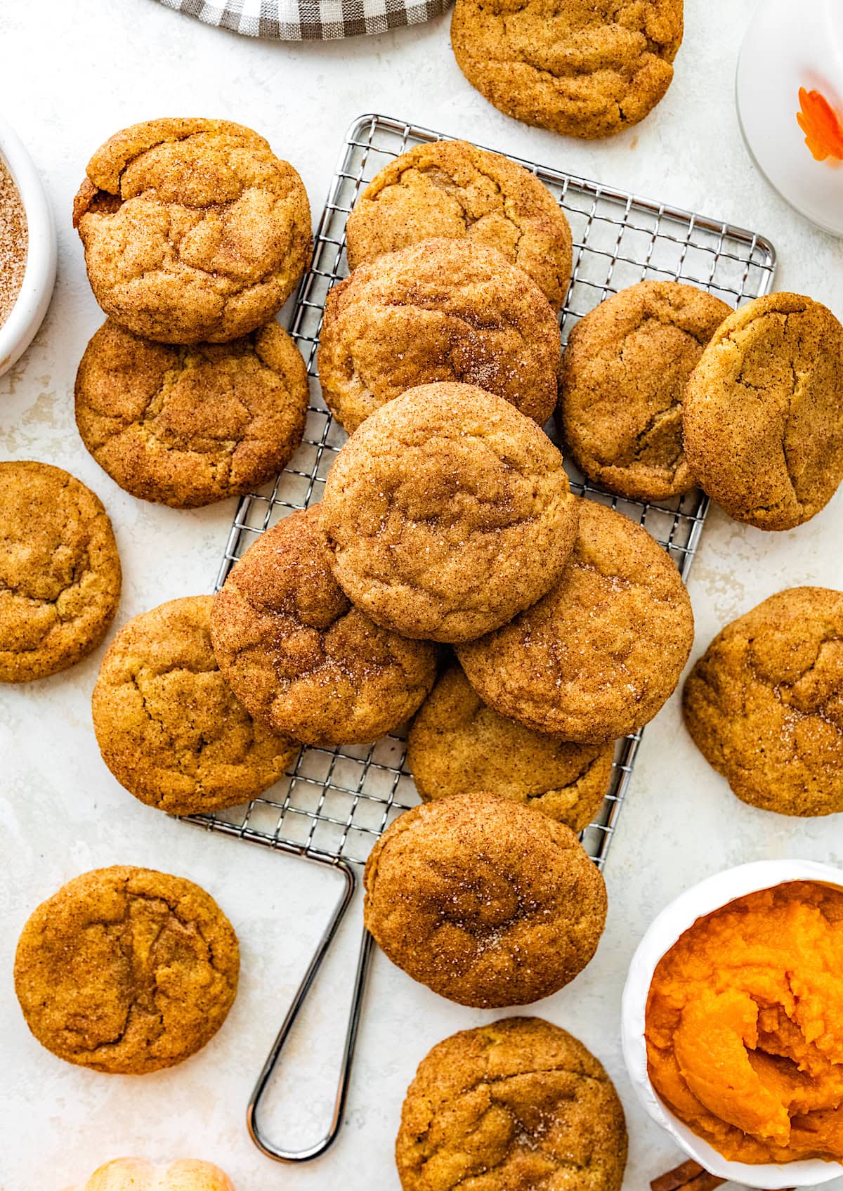 pumpkin snickerdoodle cookies on cooling rack with bowl of pumpkin. 