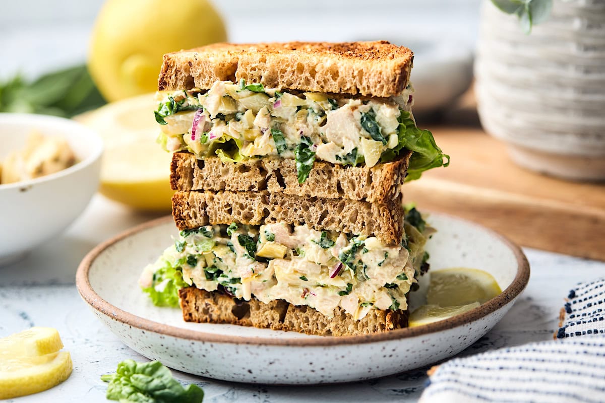 spinach artichoke chicken salad sandwich stacked on a plate.
