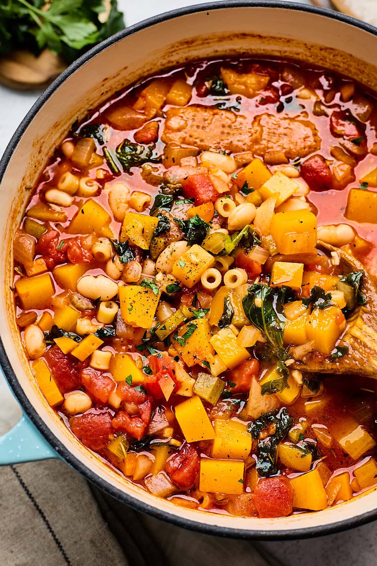 fall minestrone soup in large pot with wood ladle.