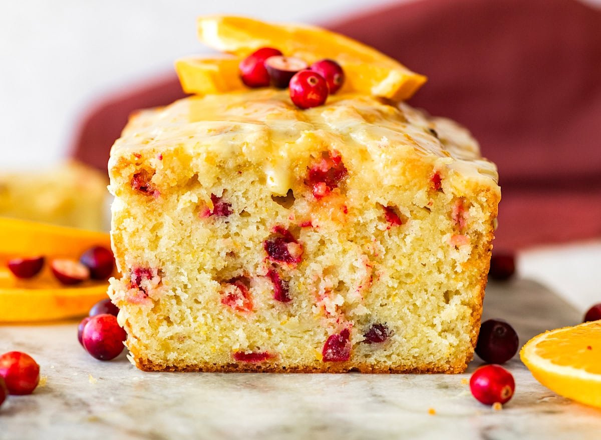 orange cranberry bread with fresh cranberries and orange glaze on marble board. 