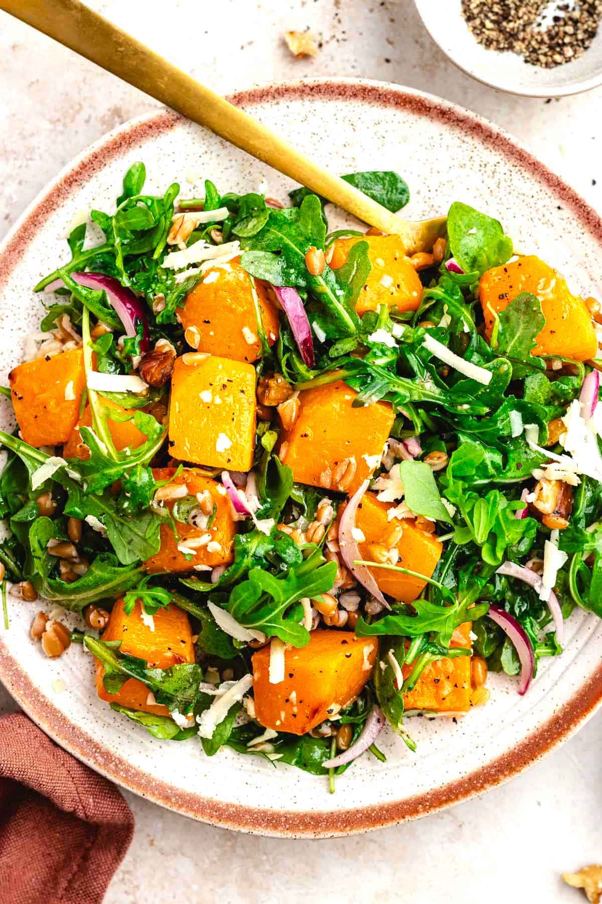 close up of roasted butternut squash salad on plate with fork.