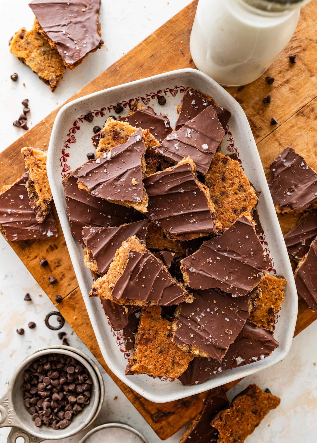 chocolate chip cookie bark pieces with flaky sea salt in platter on wood board.