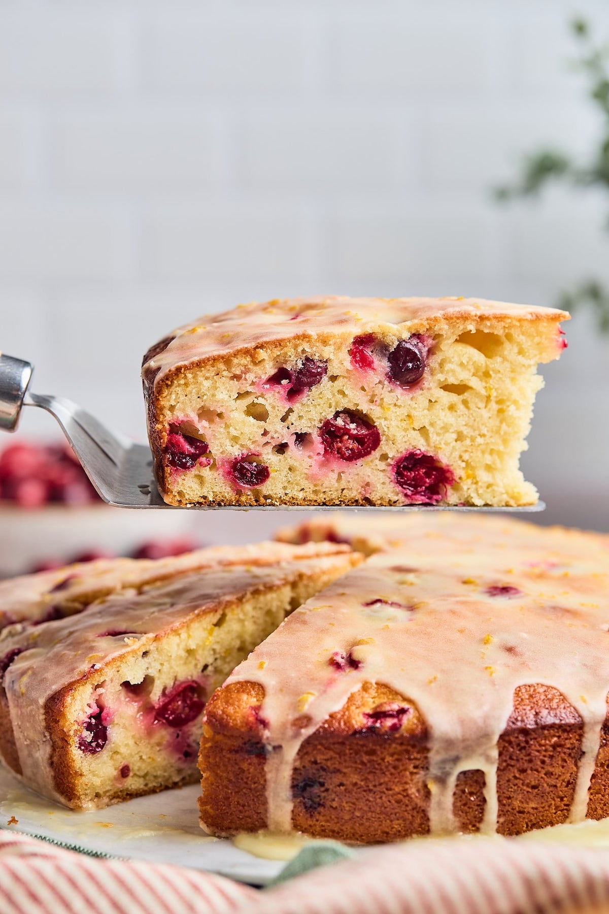 piece of cranberry orange cake being cut and lifted out of the cake.