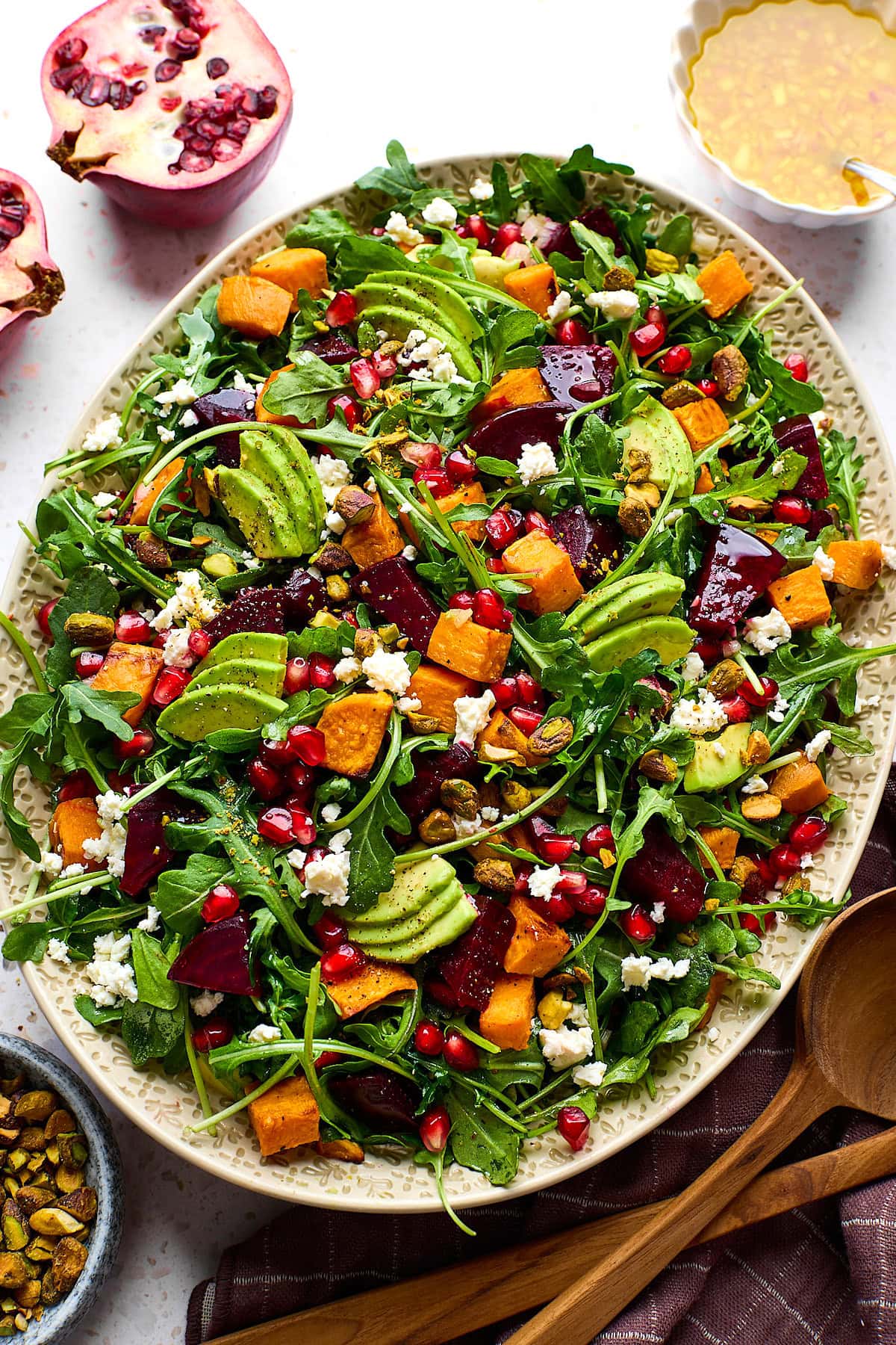 Roasted Sweet Potato and Beet Salad with goat cheese, avocado, pomegranate, and pistachios on platter.