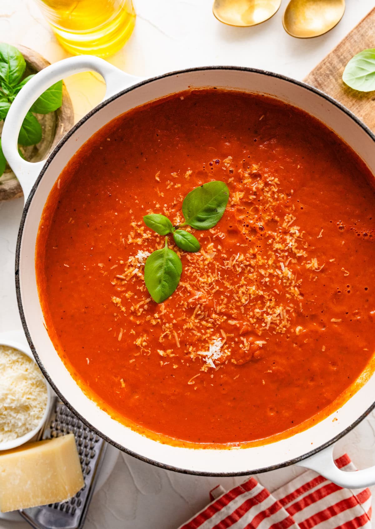 creamy tomato basil soup in pot with parmesan cheese and fresh basil.