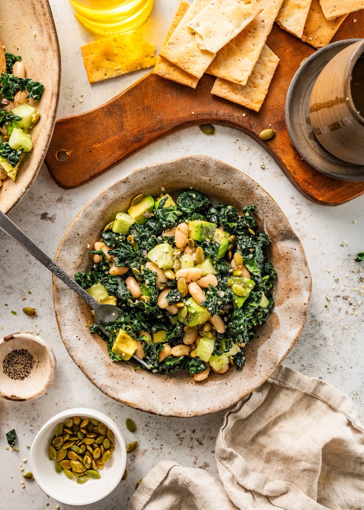 kale and white bean salad in bowl with fork being served with crackers. 