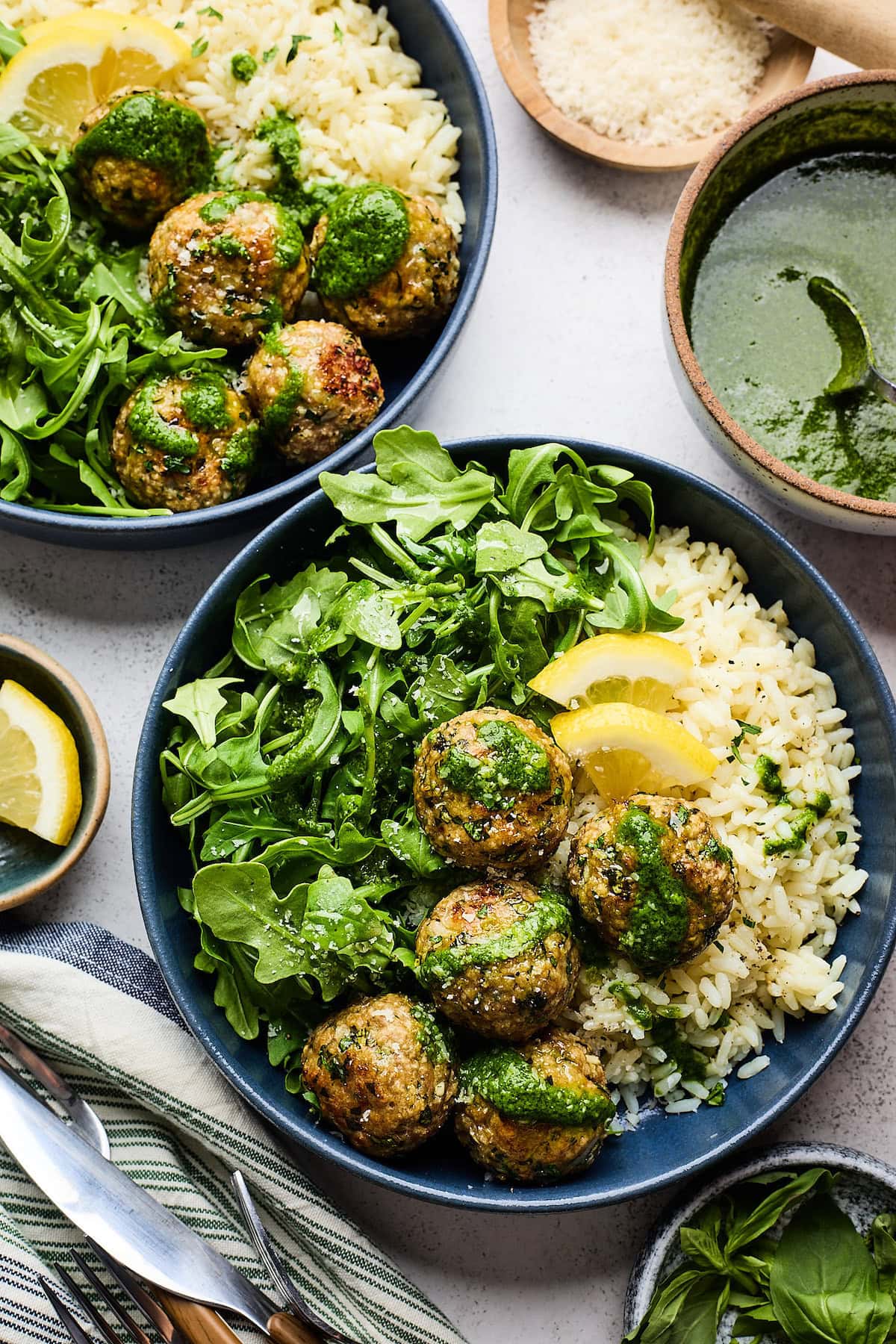 lemon herb meatballs in bowl with arugula, rice, basil vinaigrette, and lemon slices.