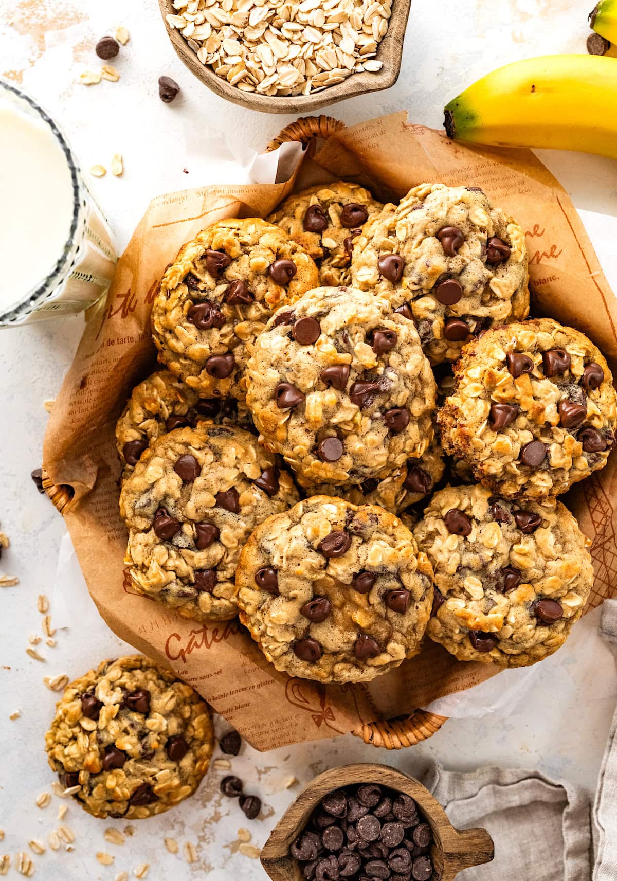 banana oatmeal chocolate chip cookies in basket with glass of milk. 