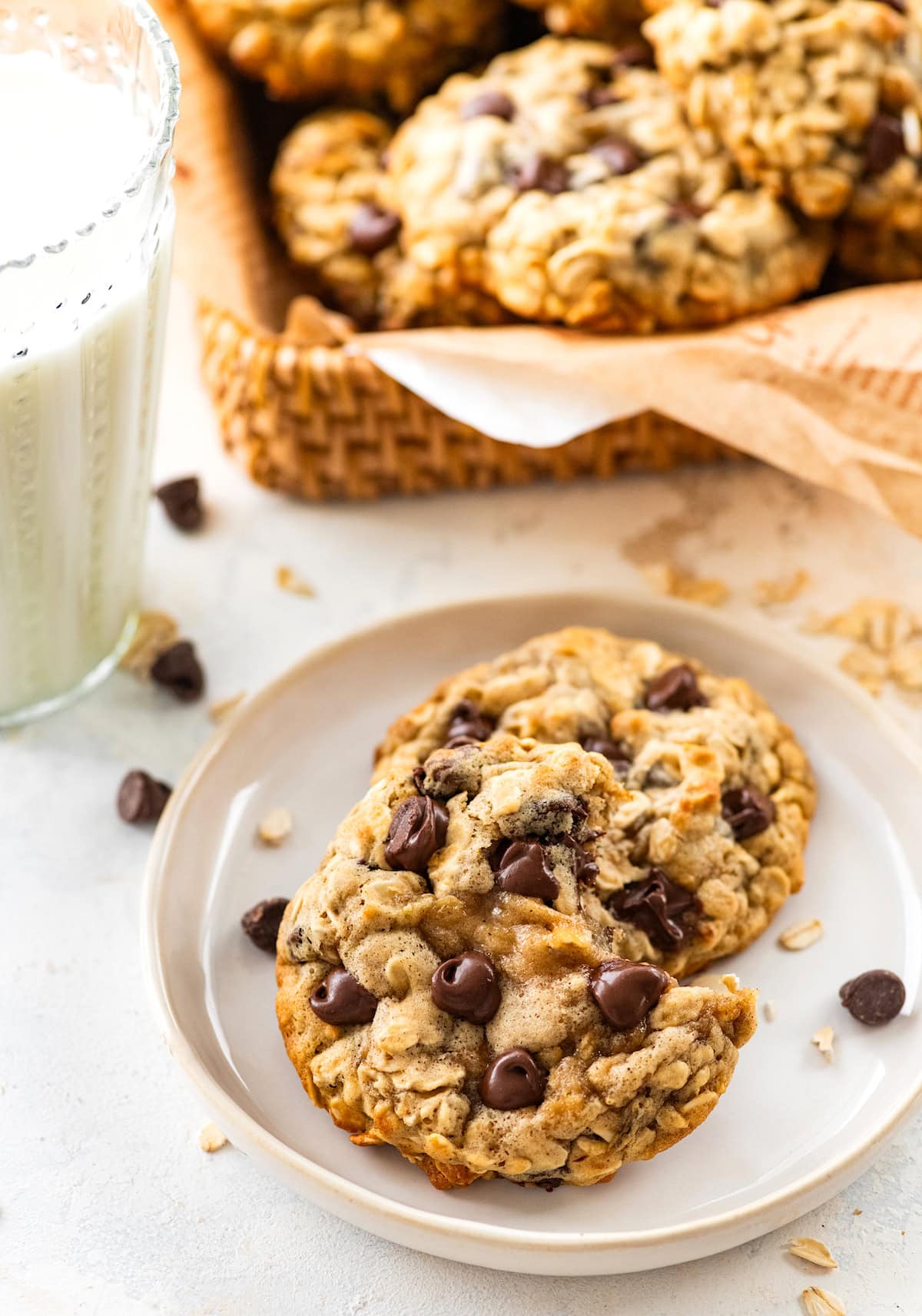 two banana oatmeal chocolate chip cookies on plate with glass of milk. 