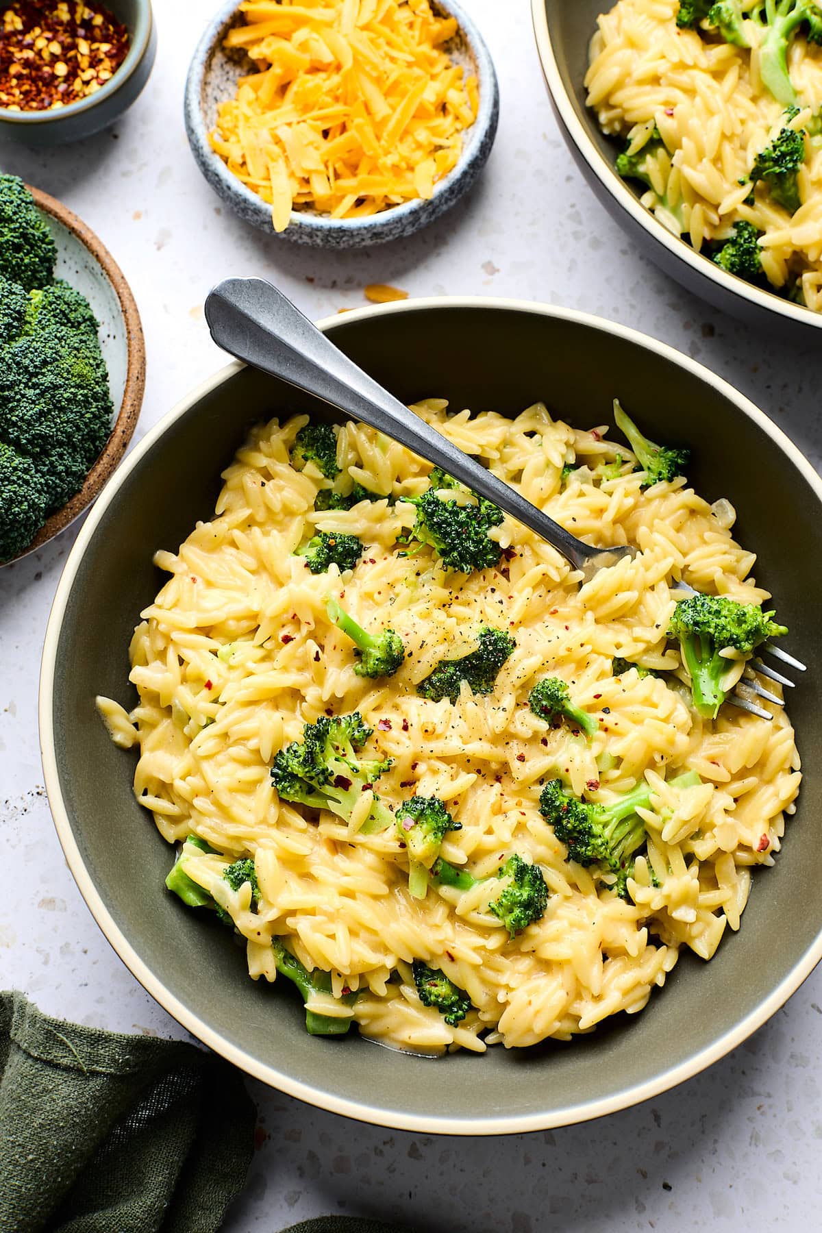 broccoli cheddar orzo in bowl with fork.
