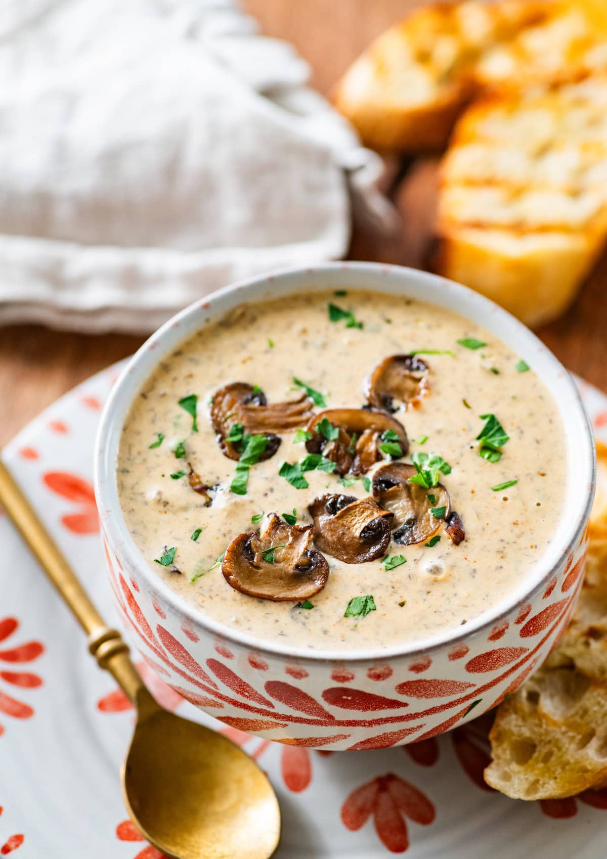 creamy mushroom soup in bowl with a spoon and crusty bread on the side.
