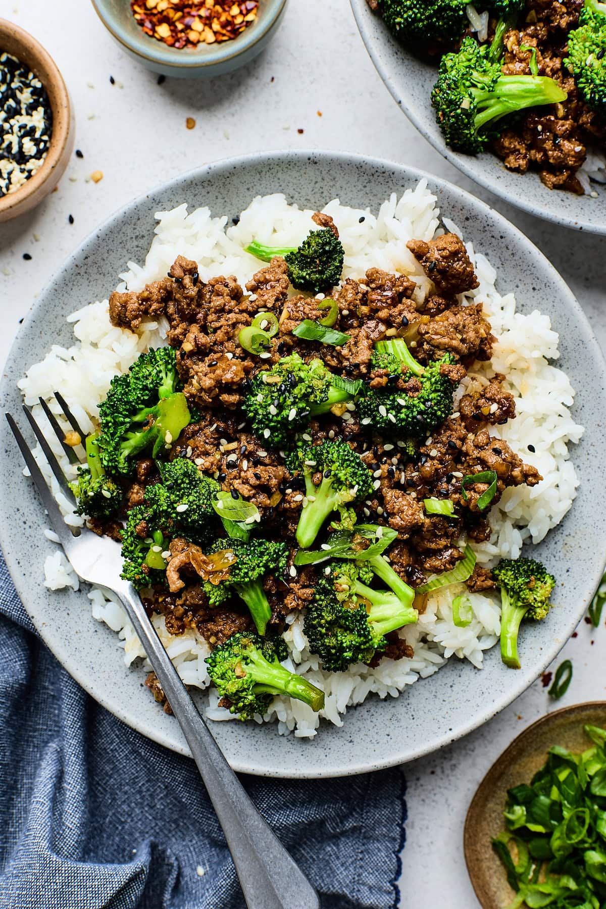 ground beef and broccoli on a plate of rice with a fork.