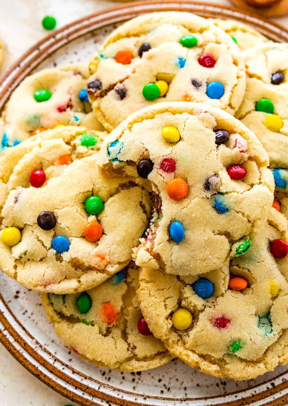close up of M&M sugar cookies on plate with a bite taken out of a cookie.