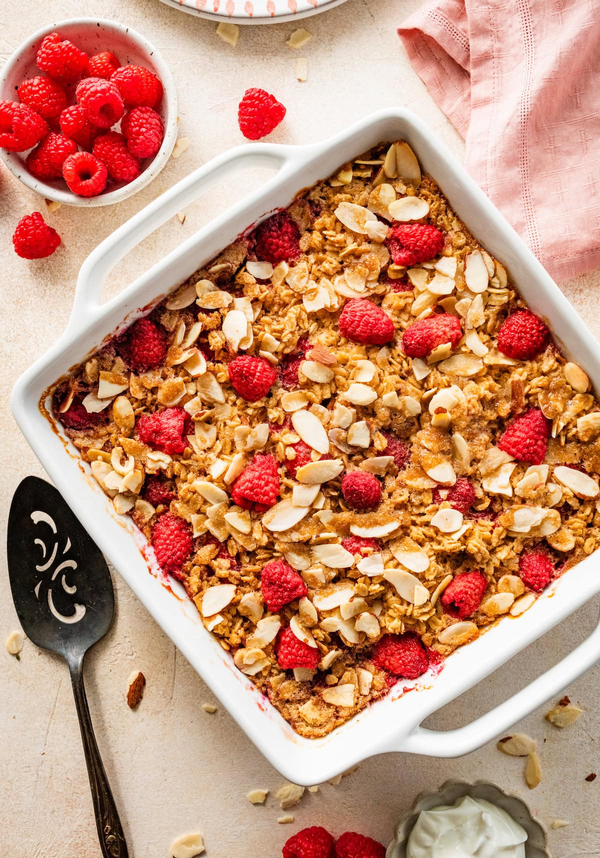 raspberry baked oatmeal in pan with sliced almonds and fresh raspberries.