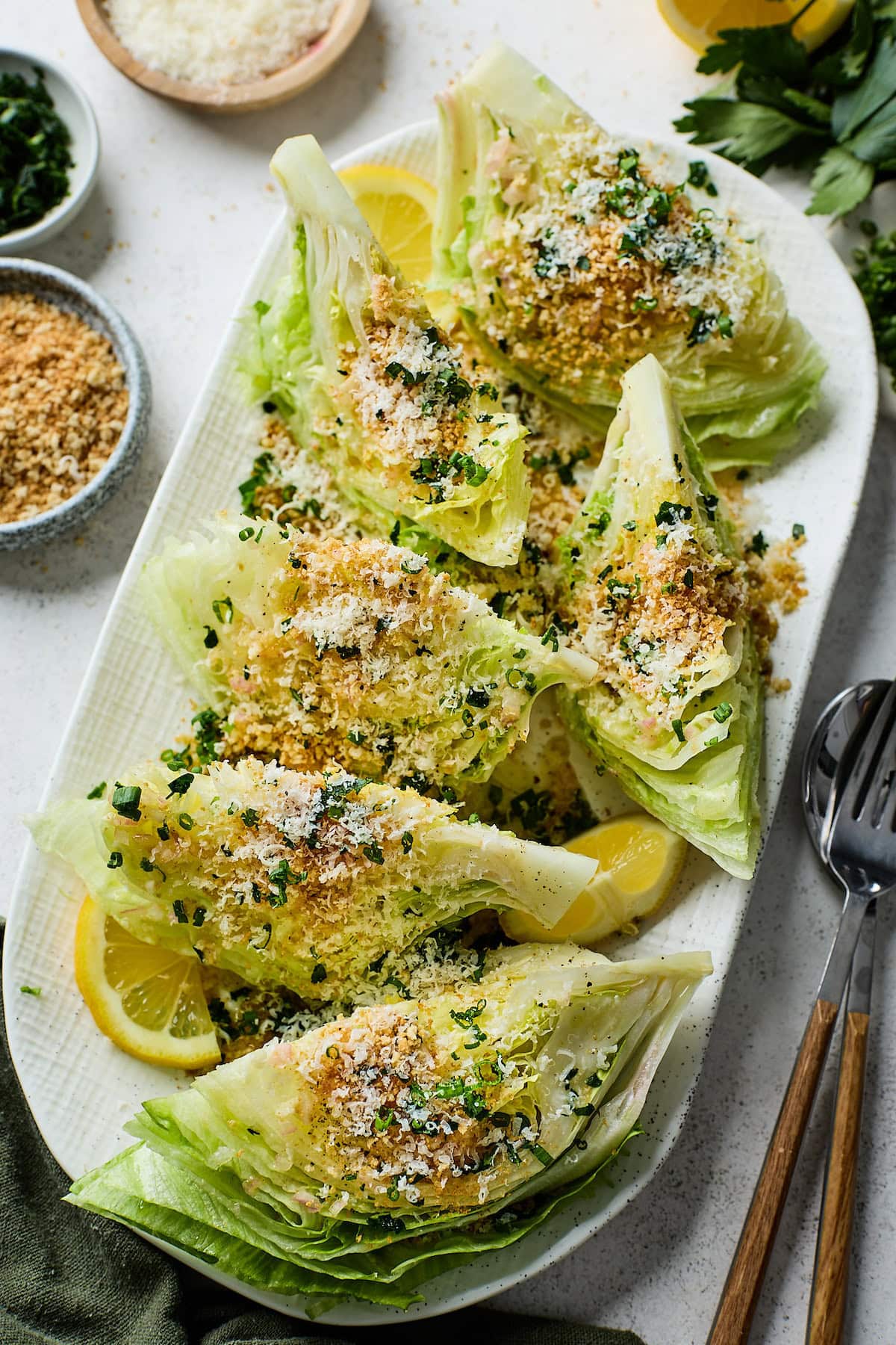 lemon parmesan wedge salad with breadcrumbs and lemon wedges on platter.