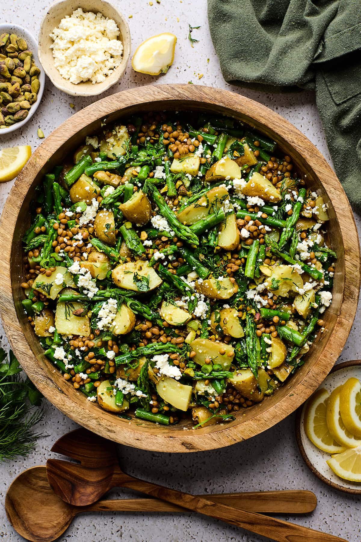 Potato Asparagus Lentil Salad with Lemon Dijon Dressing in wood bowl with feta cheese and herbs.
