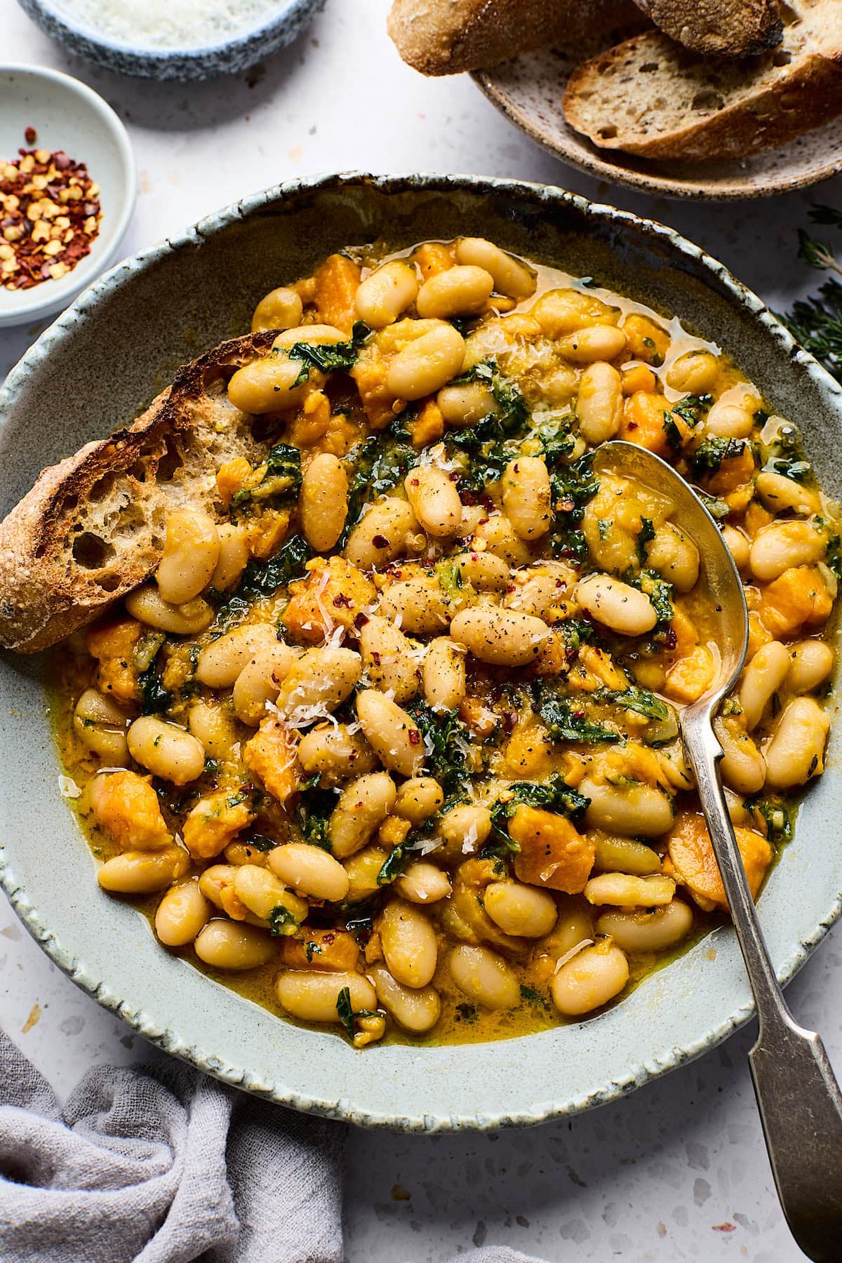 sweet potato and white beans in bowl with spoon and crusty bread.