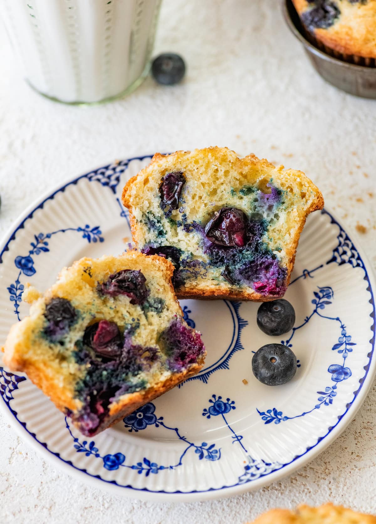 blueberry yogurt muffin cut in half on plate. 