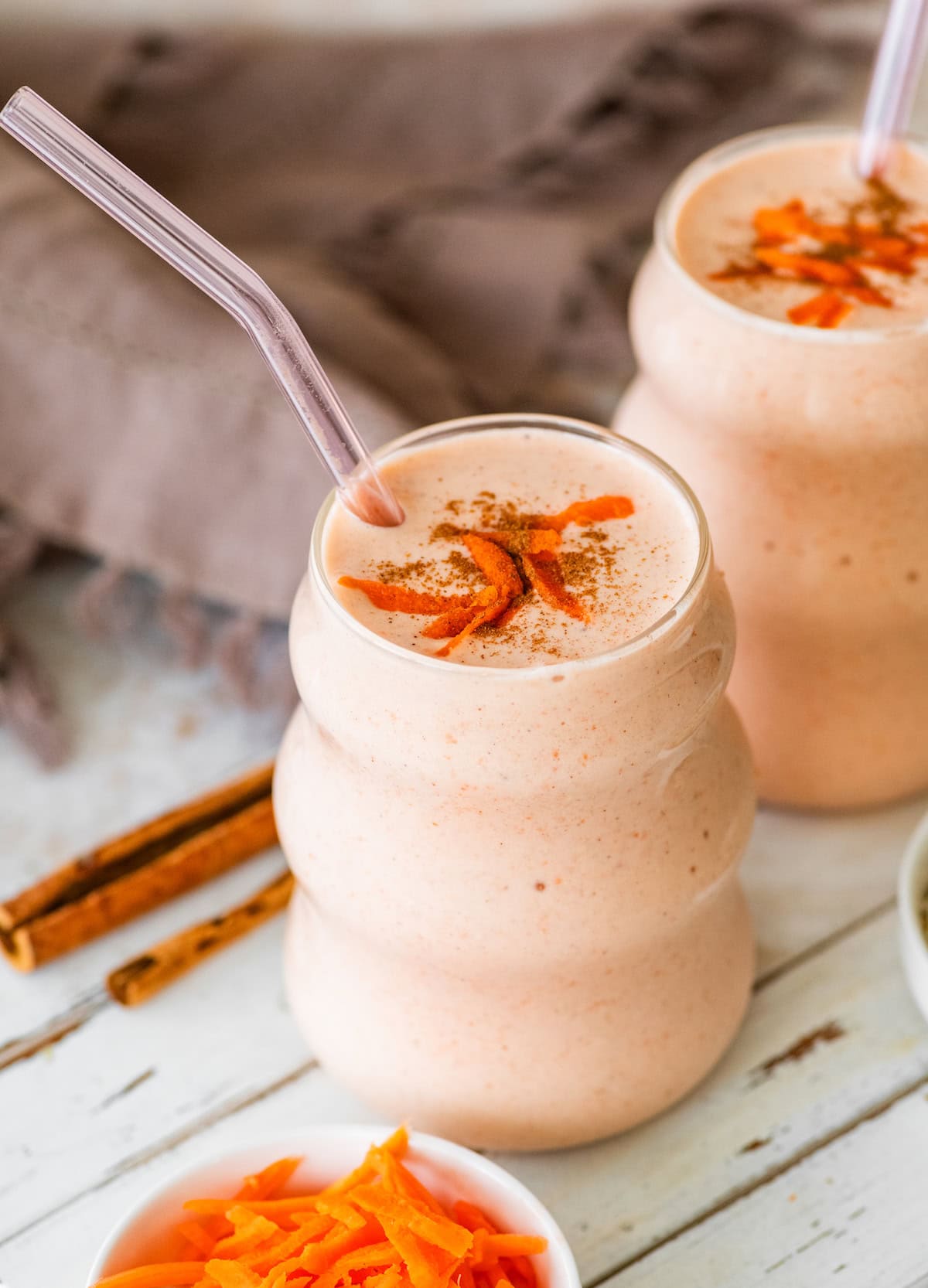 carrot cake smoothie in glass with straw.